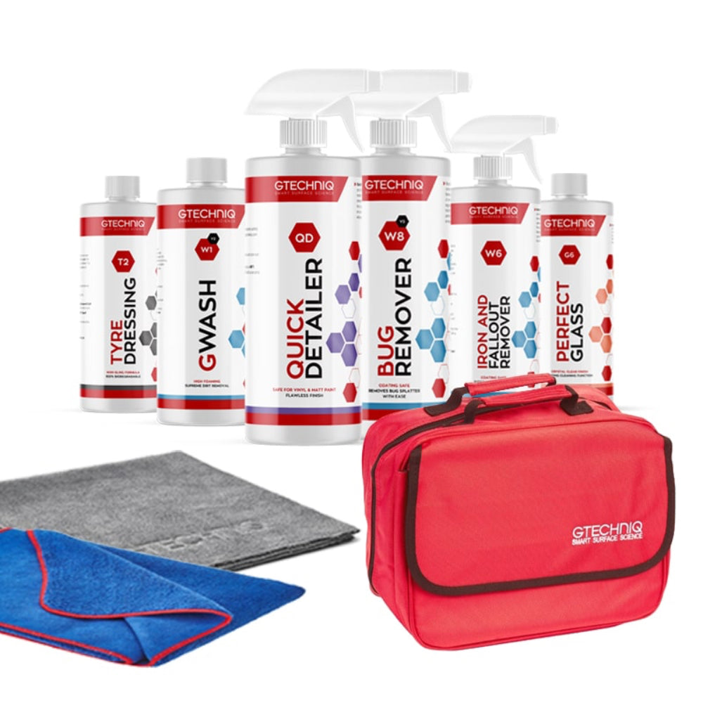 A collection of car maintenance products from Gtechniq, including a bottle of GWash, a spray bottle of Quick Detailer, a bottle of G6 Perfect Glass, a smaller bottle of Iron and General Fallout Remover, a smaller bottle of Tyre Dressing, a smaller bottle of W8v2 Bug Remover, two microfiber buff cloths, and a large red kit bag with the Gtechniq logo.
